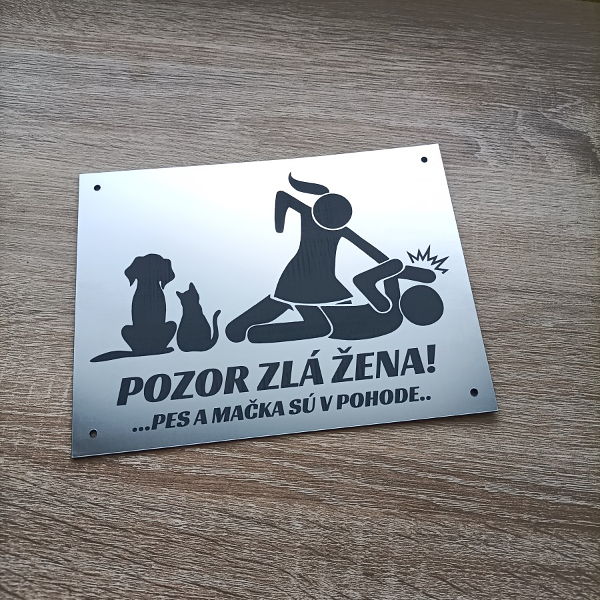 Strieborná humorná tabuľka Pozor zlá žena so siluetami psa a mačky na drevenej podlahe