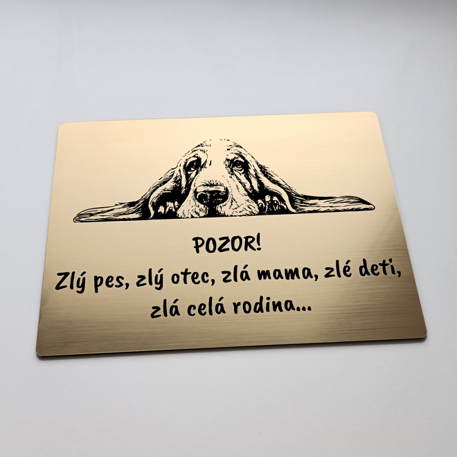 Zlatá tabuľka s ležiacim basetom a vtipným nápisom Zlý pes, zlá celá rodina