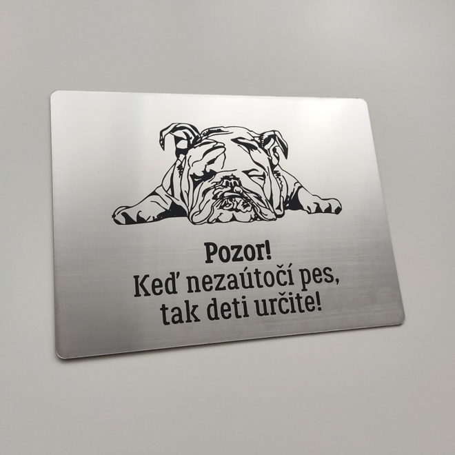 Strieborná tabuľka s ležiacim buldogom a vtipným nápisom Keď nezaútočí pes, tak deti určite