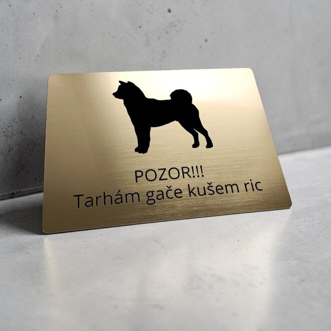 Zlatá tabuľka so siluetou shiba inu a vtipným nárečovým nápisom